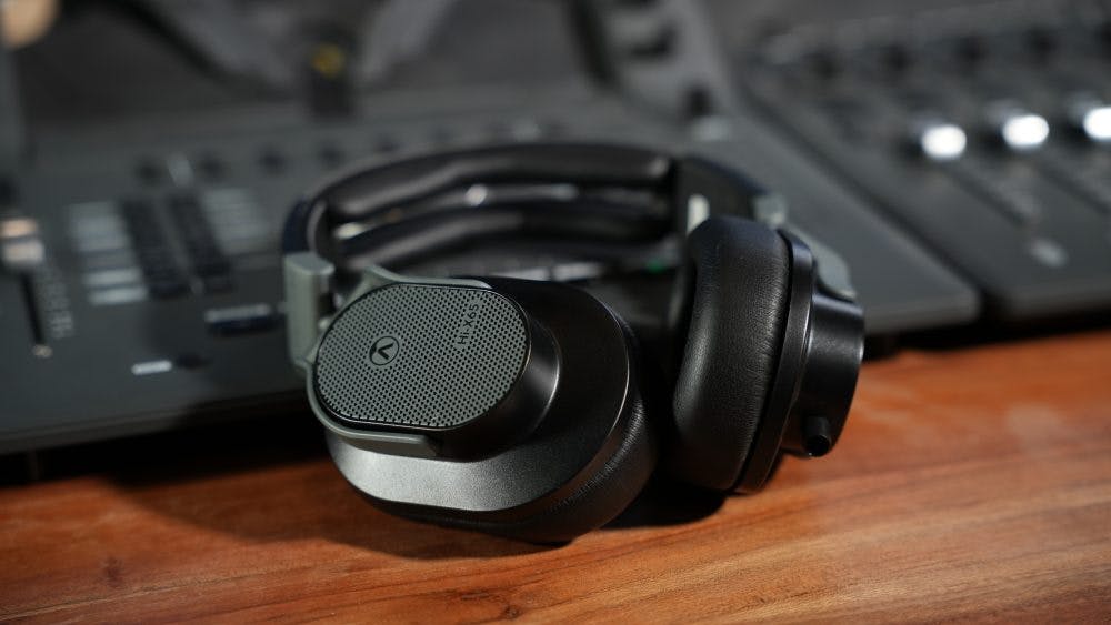 Austrian Audio Hi-X65 headphones on wooden desk with studio equipment background