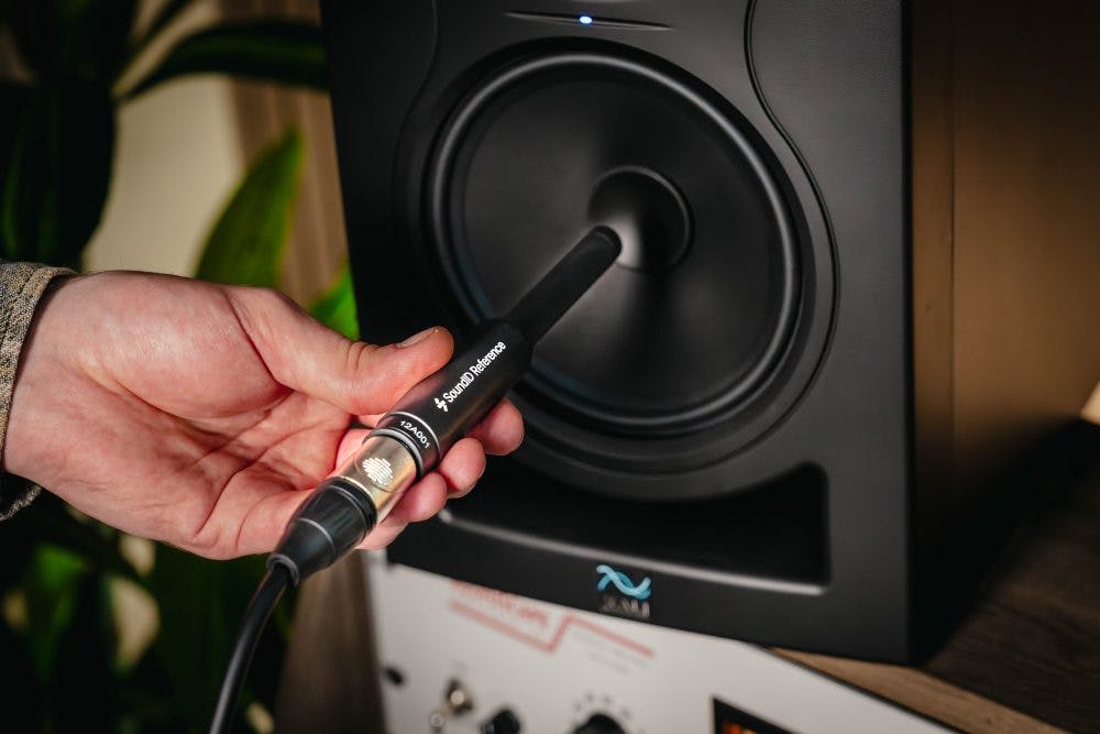Hand positions SoundID Reference calibration microphone at studio monitor driver during ORIA Mini room measurement
