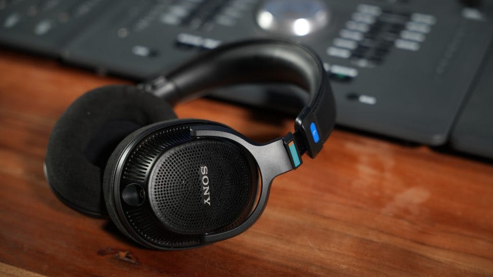 Sony MDR-MV1 headphones folded flat showing lightweight design with blue accents on studio desk