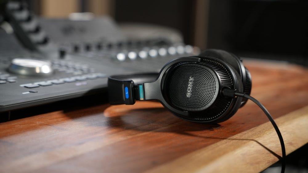 Sony MDR-MV1 headphones side view showing mesh grille and blue accents in studio setup